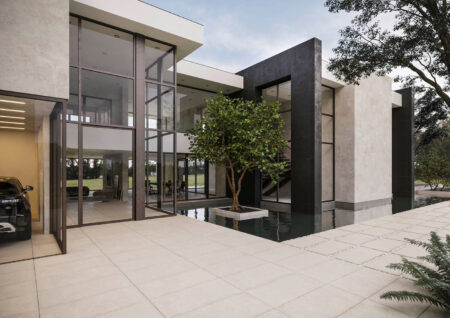 Modernes Haus mit Glasfenstern, Wasserbecken, Baum im Innenhof und teilweise sichtbarem Auto.