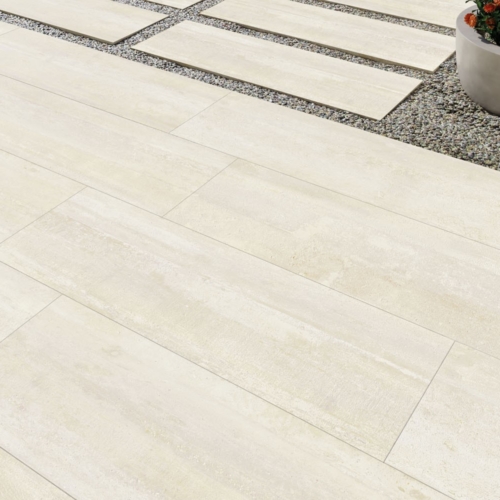 Terrasse mit hellen Steinplatten, Kiesbett und rundem Pflanzkübel mit orangefarbenen Blumen.