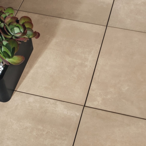 Rechteckiger schwarzer Pflanzkübel mit Sukkulenten und Kies auf beigen Fliesen.