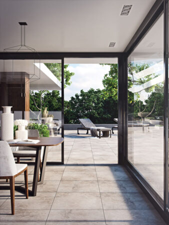 Moderner Innenraum mit Glaswänden, Esstisch, großer Terrasse und Liegestühlen.